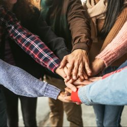 Happy young friends having fun stacking hands together outdoor - Youth people millennial generation concept